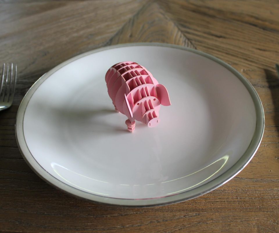 Pappschwein auf einem Teller mit Messer und Gabel